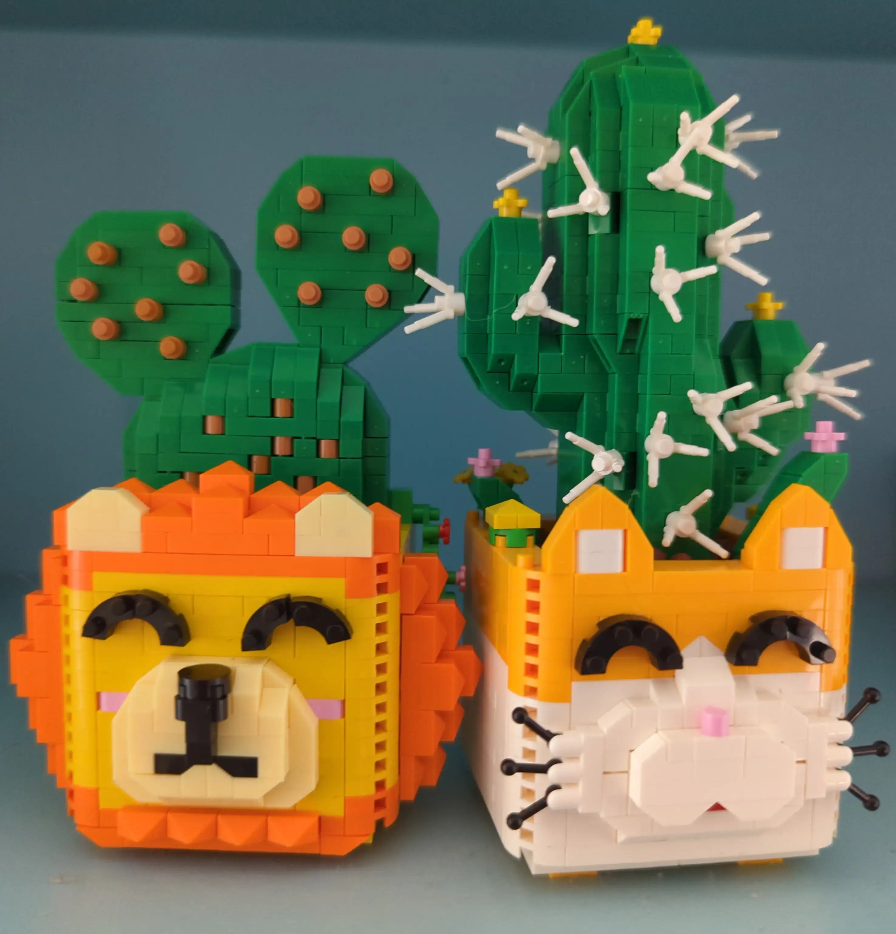 Two potted cacti, one pot lion-shaped, the other cat-shaped, made from very tiny studded bricks