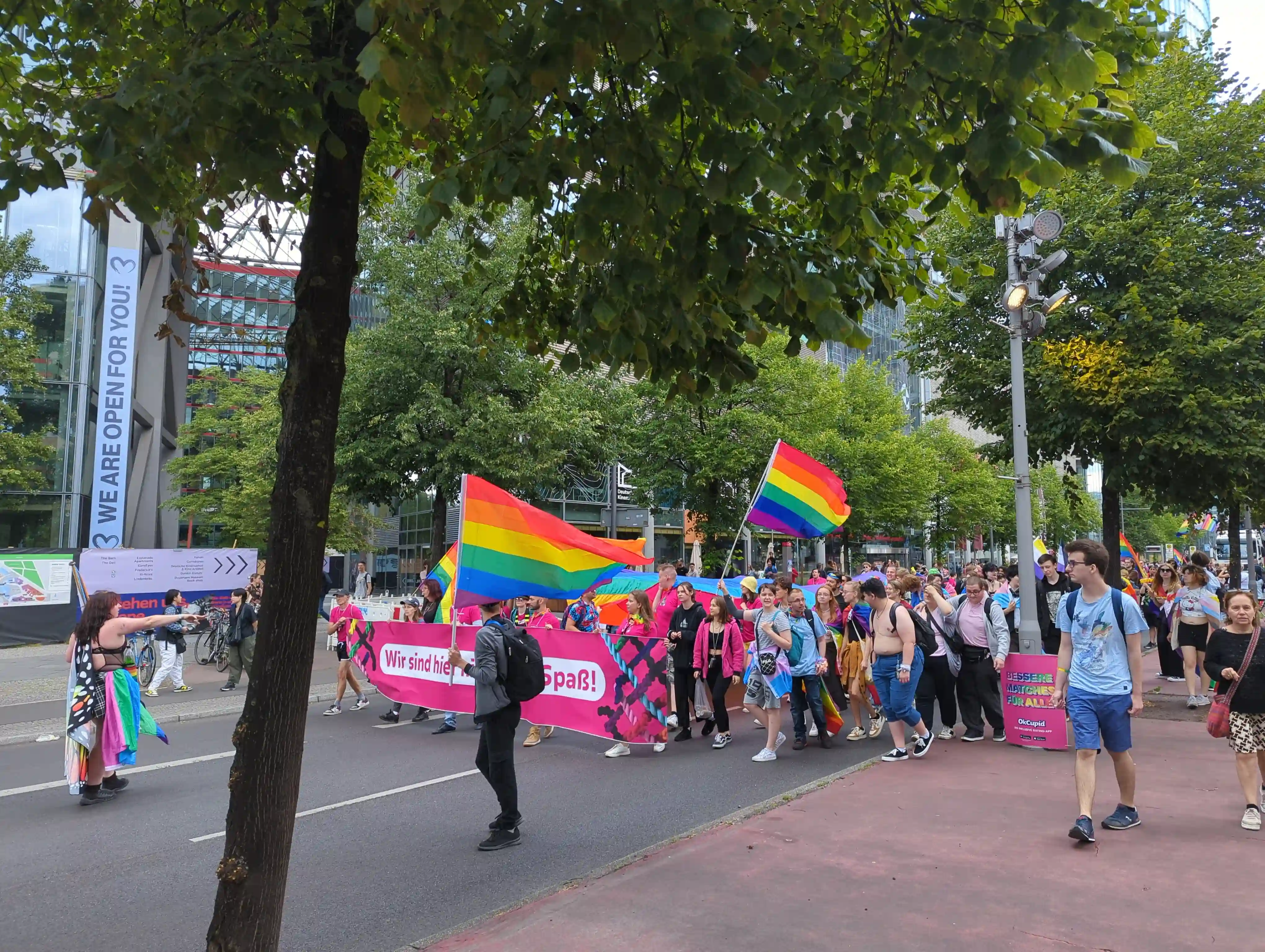 Front of the parade, people are carrying an oversized rainbow flag, and a banner saying "Wir sind hier nicht zum Spaß!"